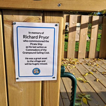 A memorial notice attached to the wooden pirate shape play area.