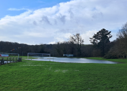The recreation ground showing a small lake in place of the football field. There are blue skies following all the heavy rain.
