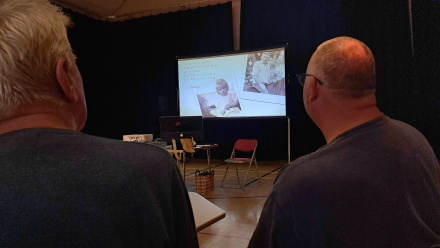over the shoulder shot of two men watching a video