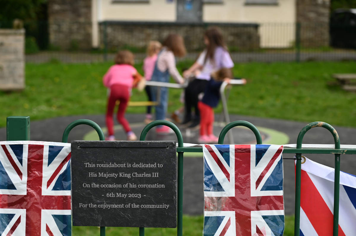 Photo of the plaque on the railings with children on the new roundabout in the background.